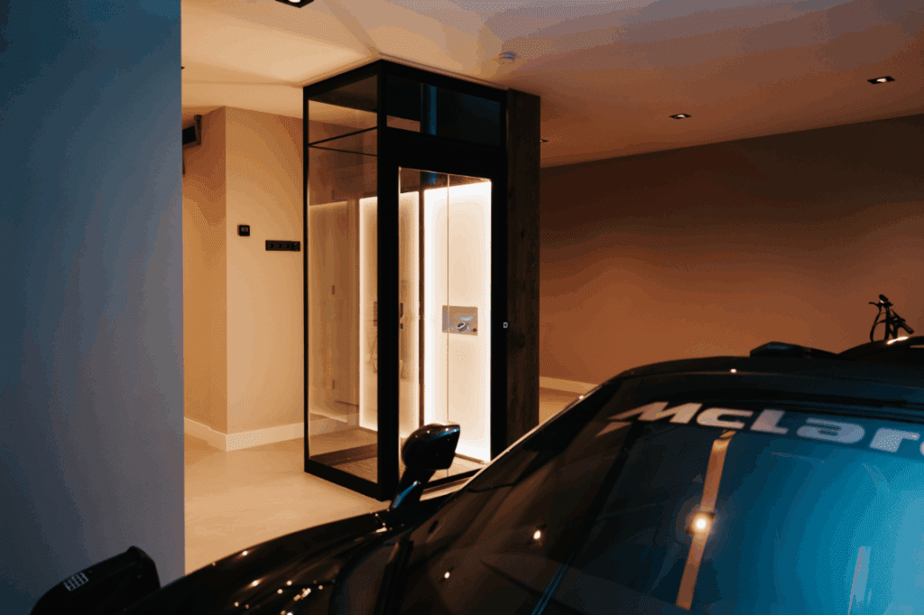 Luxe huislift met glazen wanden geplaatst in een ruime garage met designafwerking.