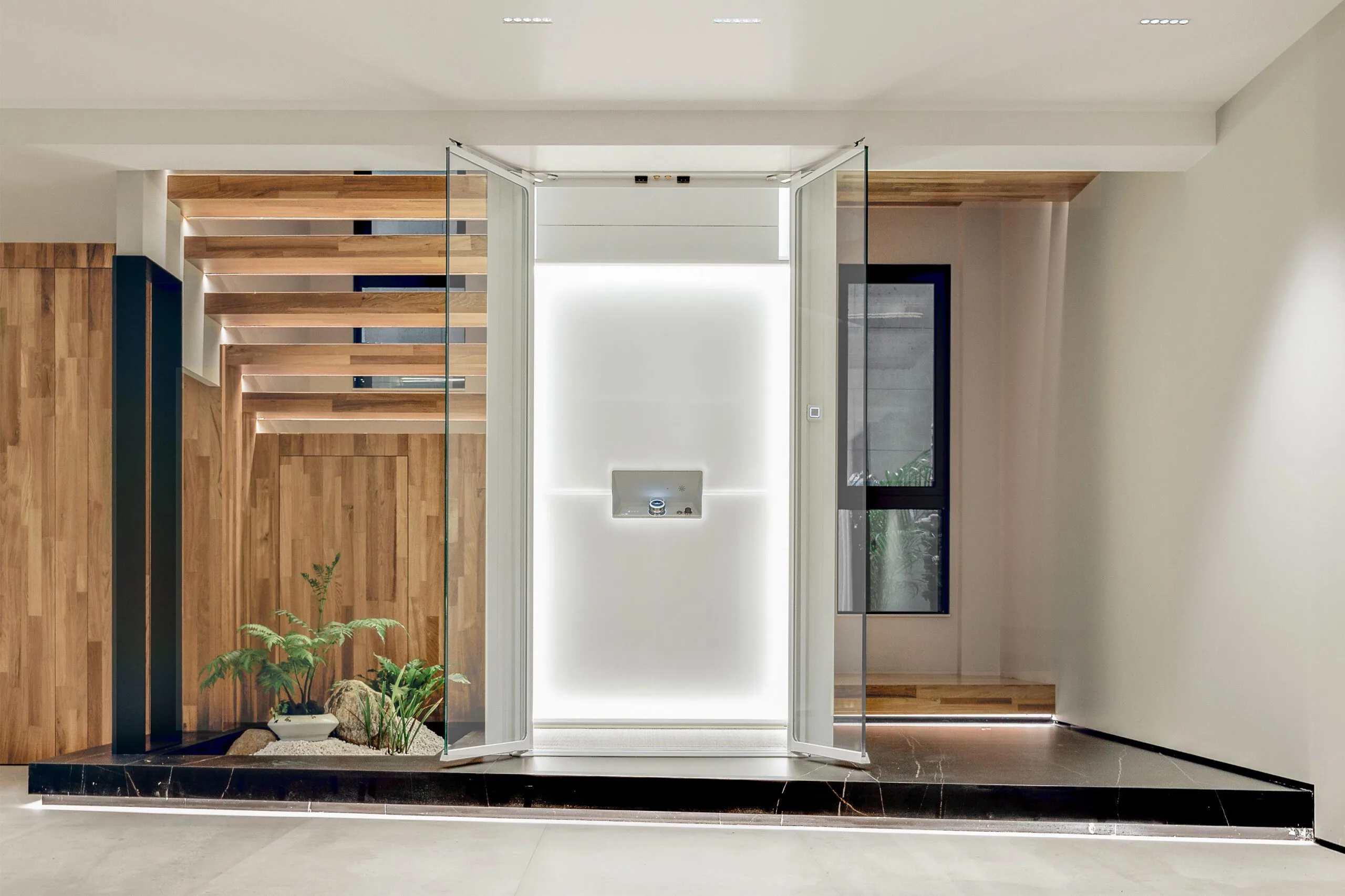 Moderne huislift met glazen deuren en een helder verlichte achterwand, geplaatst in een luxe interieur met houten accenten en ingebouwd groen.
